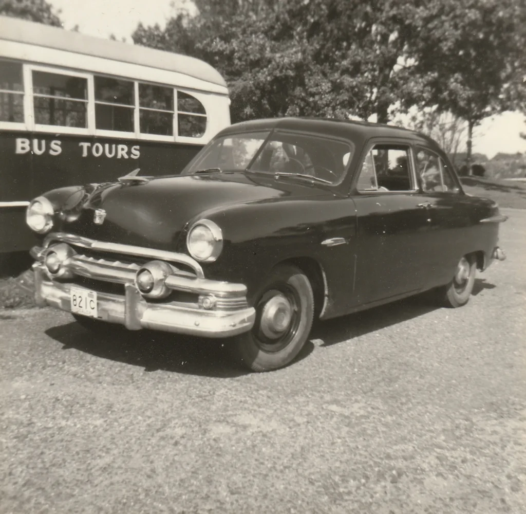 A 1950s touring car parked in front of an early Acadia Bus Tours coach in Bar Harbor