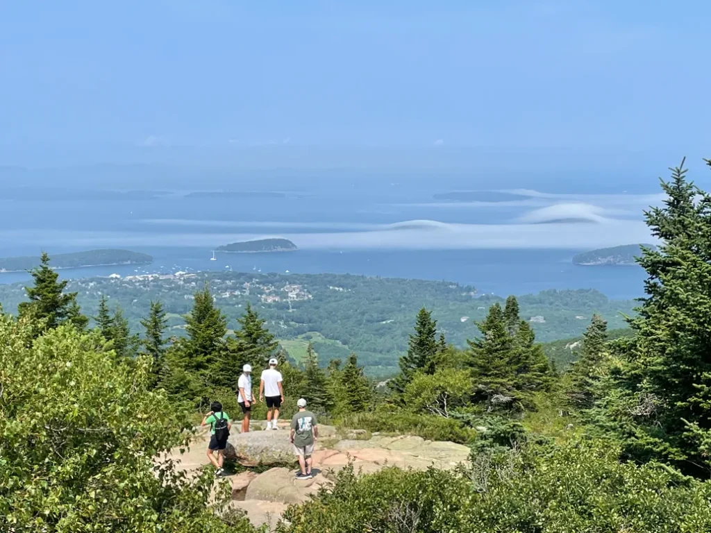 Visitors on the granite summit of Cadillac Mountain looking out over low fog banks above Frenchman Bay