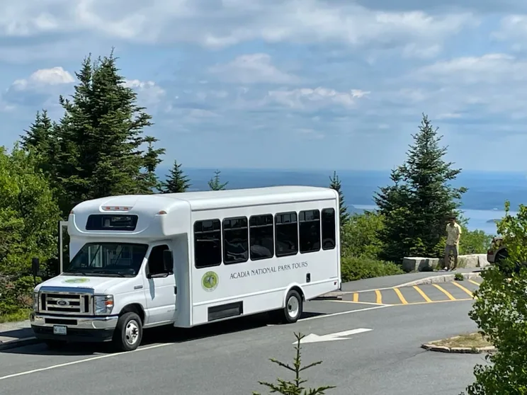 The Acadia National Park Tours mini-coach at a Cadillac Mountain pullout with visitors at the stone wall overlook