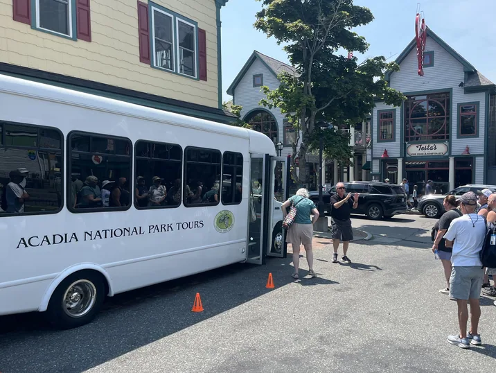 Guests boarding an Acadia National Park Tours coach with their guide on a downtown Bar Harbor street