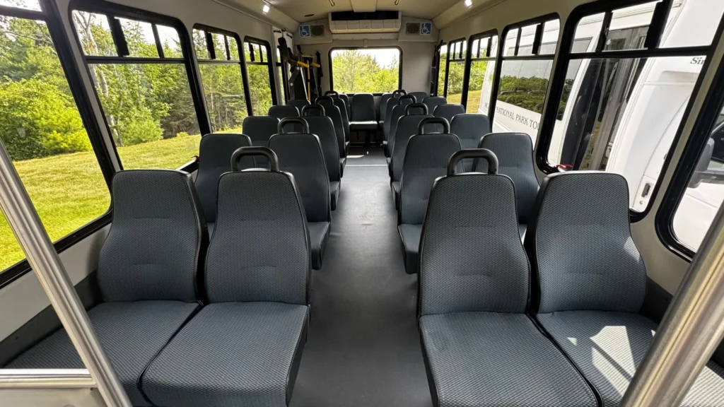 Rows of upholstered seats and large passenger windows inside an Acadia National Park Tours bus