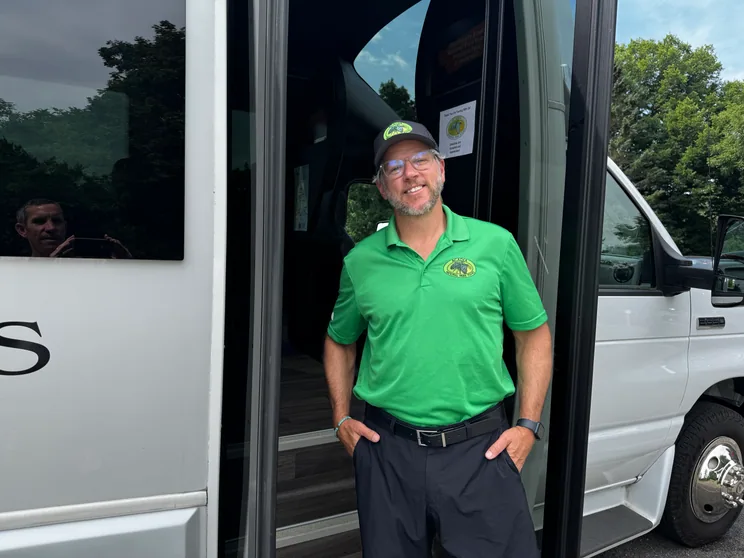 An Acadia National Park Tours guide waiting in the coach doorway to check guests aboard