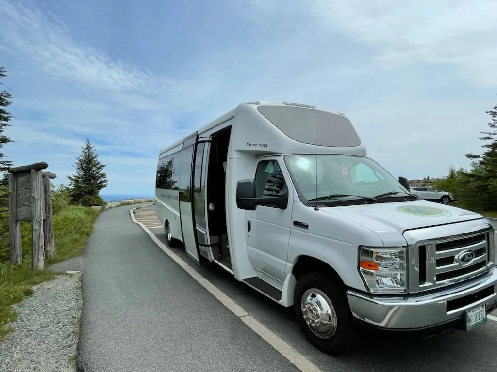 An Acadia National Park Tours mini-bus on the park loop road above the coast on a clear day