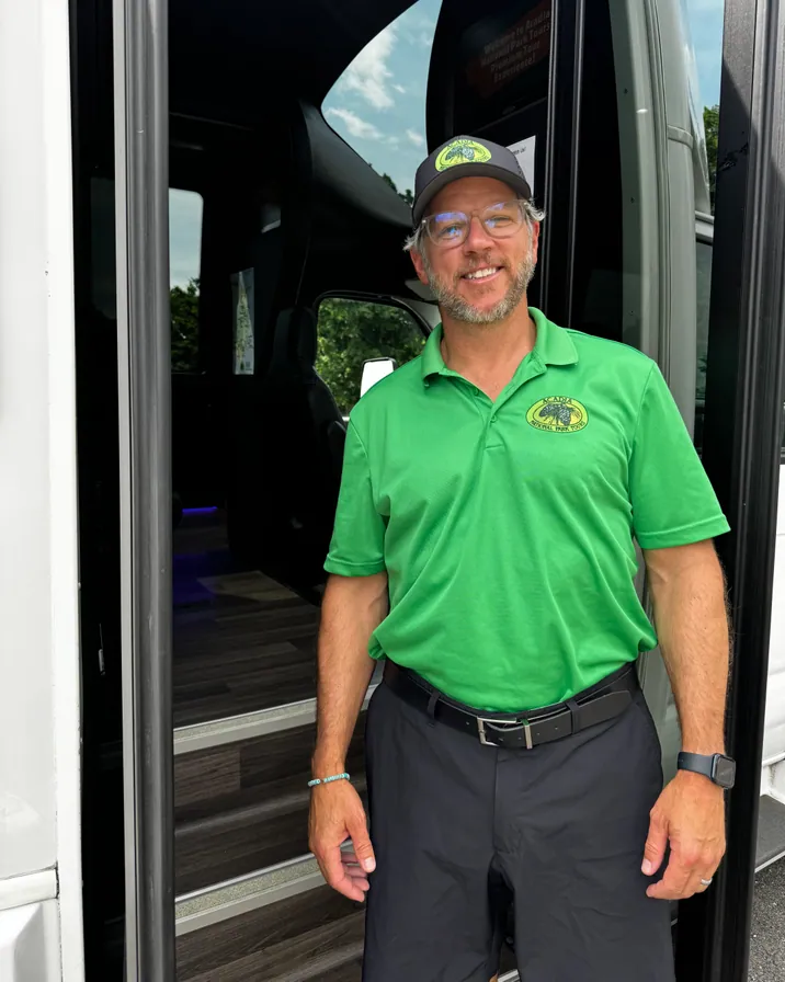 Guide Chris McGuire in a green Acadia National Park Tours polo at the front of the coach