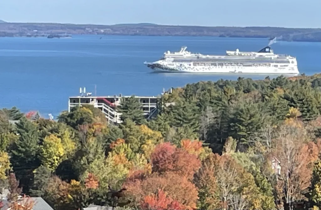 A cruise ship anchored in Frenchman Bay seen over autumn treetops in Bar Harbor