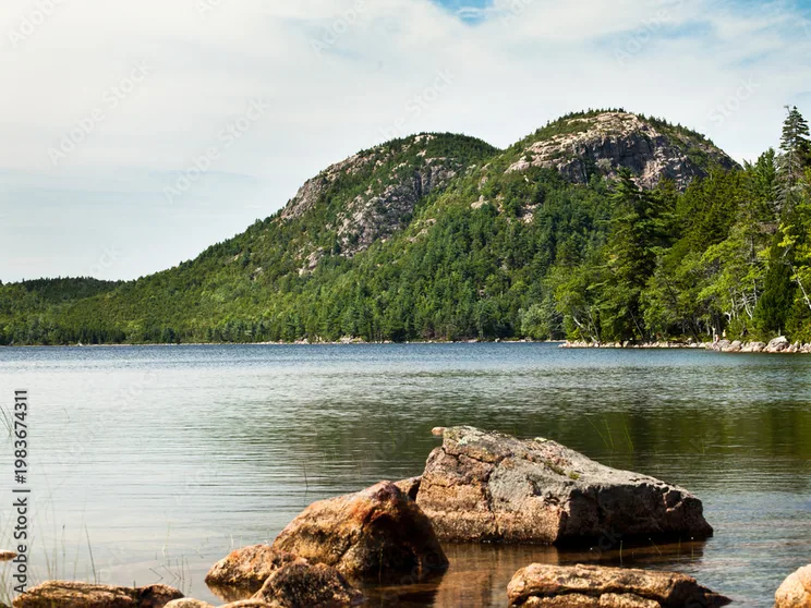 Jordan Pond's clear water with a Bubble mountain rising above the far shore