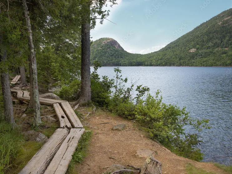The split-log shore path at Jordan Pond with a Bubble mountain rising across the water
