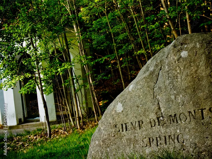 The carved Sieur de Monts Spring boulder with the historic white spring house behind it